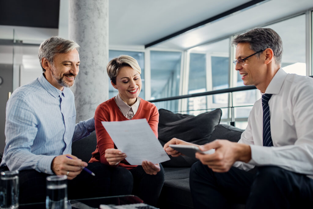 happy couple financial advisor going through plans meeting